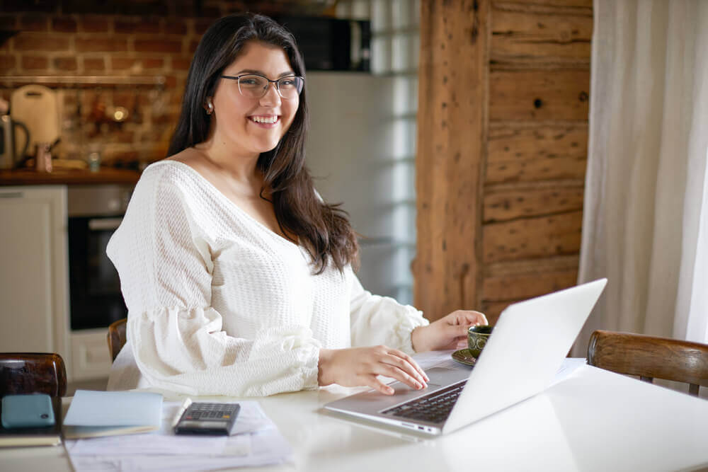 Woman at laptop smiling at the camera